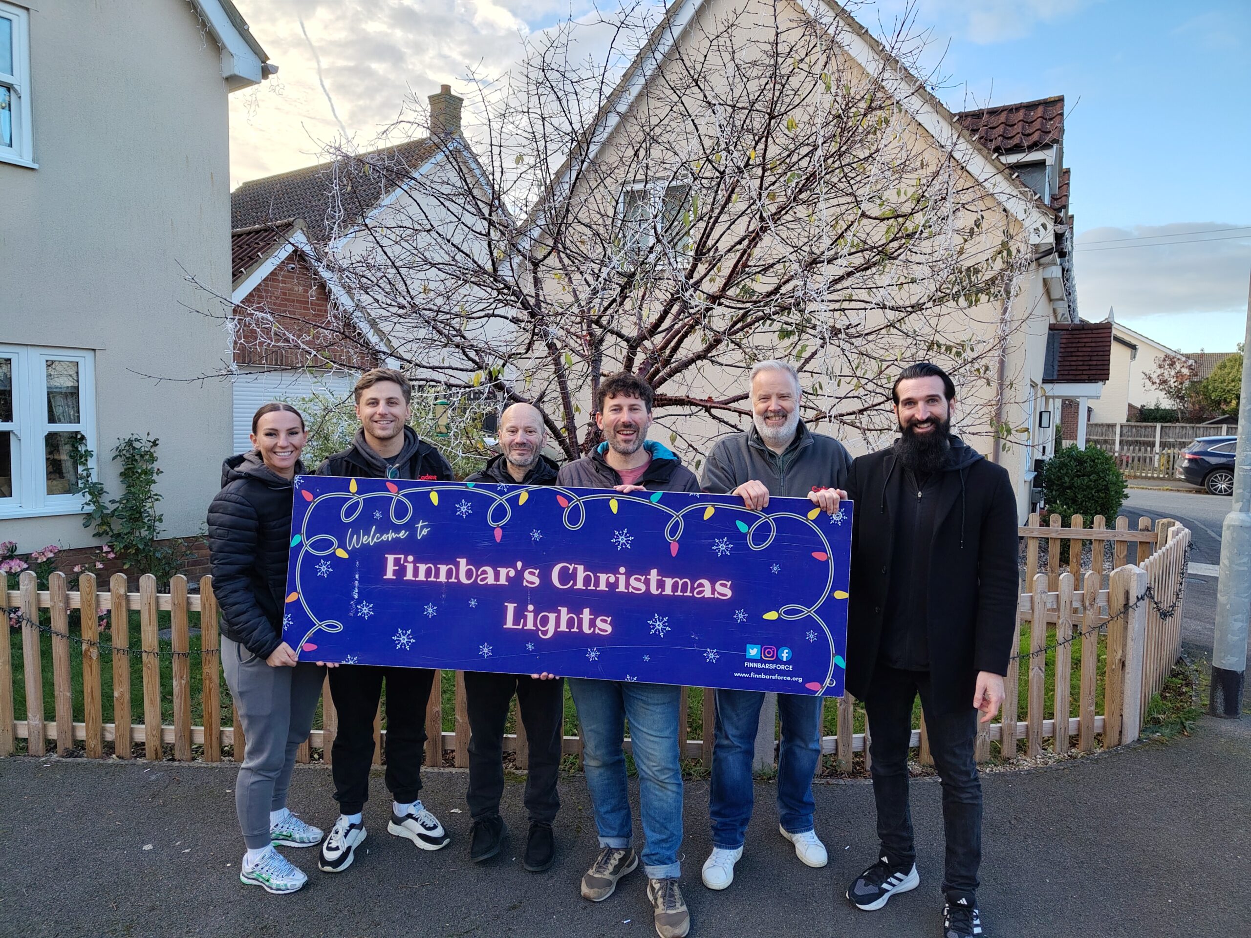 Group holding Finnbar's Christmas Lights charity banner outdoors